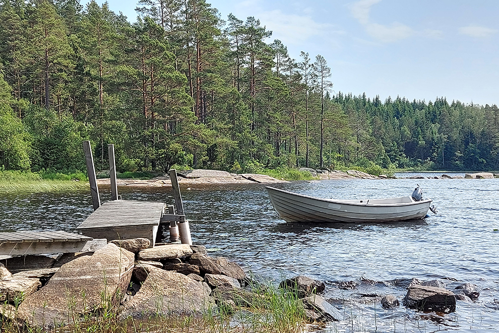 Båt vid brygga i sjö.