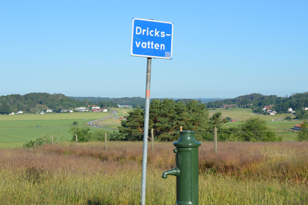 Skylt med texten "Dricksvatten" i landsbygdsmiljö.