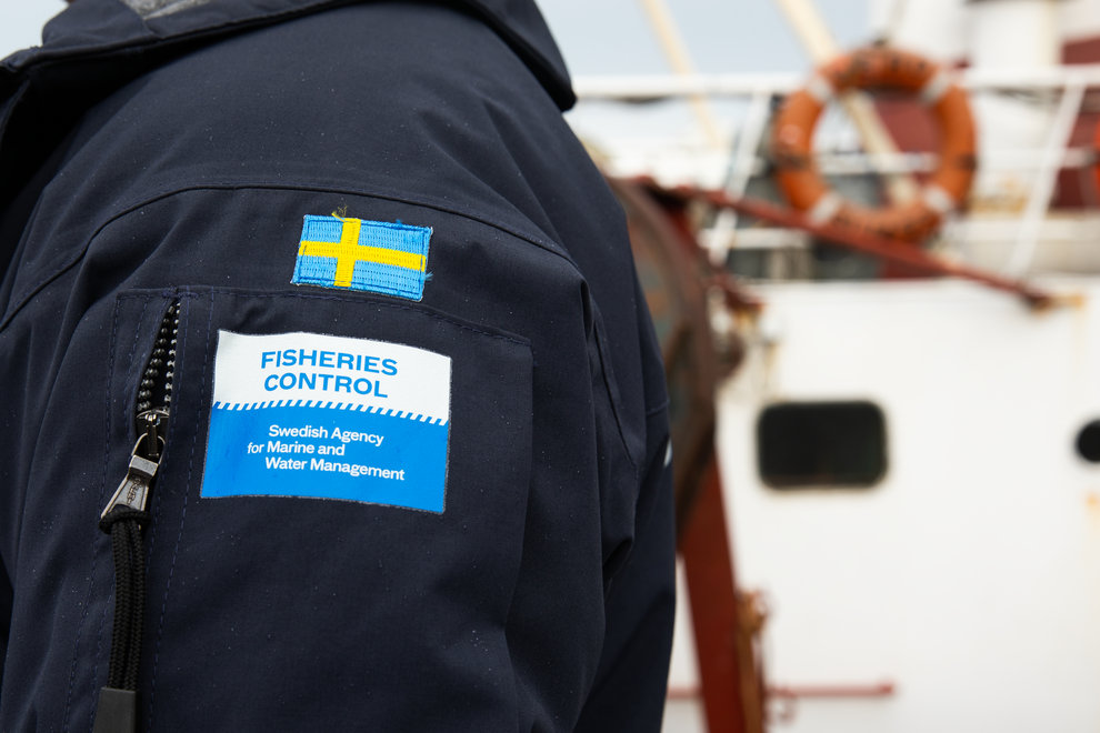 Jackärm med två emblem; en svensk flagga och en med text som det står fiskerikontroll samt Havs - och Vattenmyndigheten.